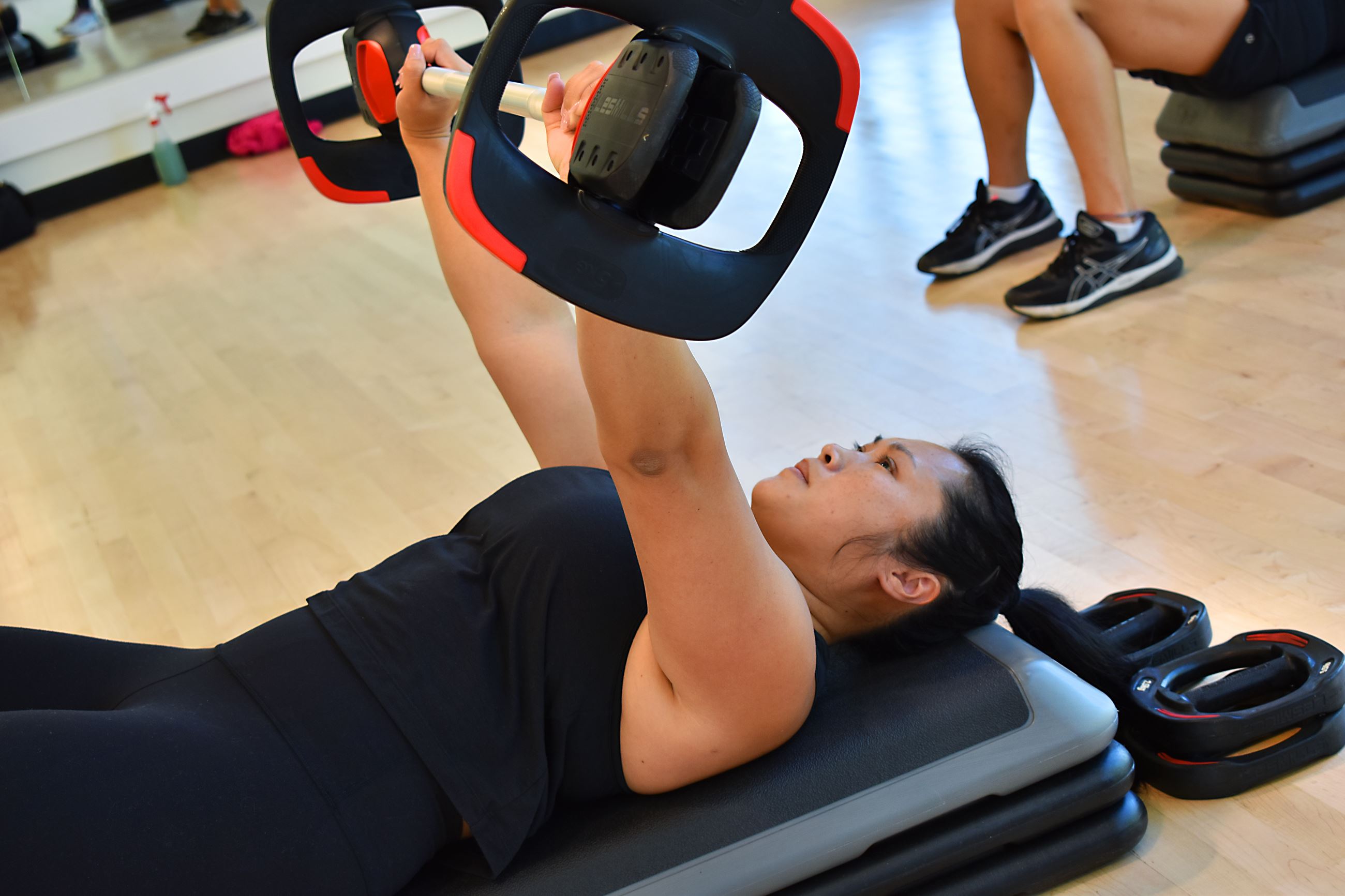 Woman in black tank top lifting weights during a class at CRC